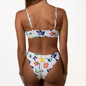 Rear view of a person in the Amore Bralette Set by Honey Swim, showcasing adjustable straps and high-waisted bottoms with colorful floral and shape prints on white, against a plain, light background.
