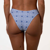 The image highlights the supportive fit of the Mykonos Squareneck Set by Honey Swim, showcasing a waist-down view of a blue mosaic tile print bikini bottom against a plain background.