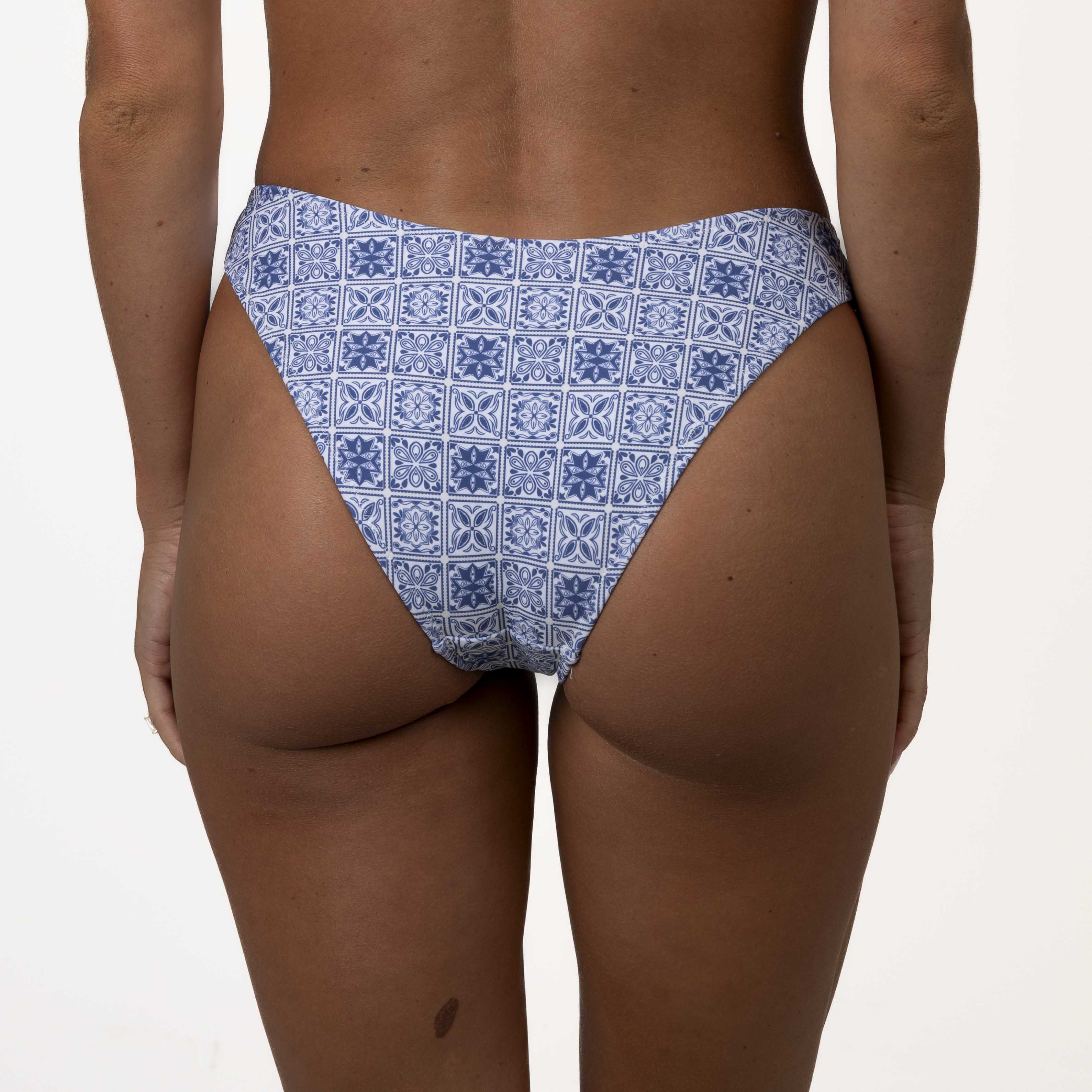 The image highlights the supportive fit of the Mykonos Squareneck Set by Honey Swim, showcasing a waist-down view of a blue mosaic tile print bikini bottom against a plain background.