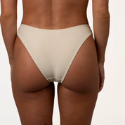 A person is shown from behind in a Honey Swim Champagne Shimmer Bandeau Set against a plain backdrop, highlighting the swimwear and their skin tone.