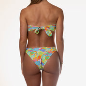 A person stands with their back to the camera in Honey Swims vibrant Eden Bandeau Set, showcasing the strapless tops tie-back design for maximum adjustability against a plain white background.
