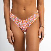 Someone wearing Poppy Ribbed Bottoms from Honey Swim stands against a plain backdrop, their hands relaxed at their sides, adorned with rings and a bracelet.
