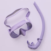 The Honey Snorkel Kit by Honey Swim showcases a purple mask with clear panoramic lenses and a snorkel with a curved design, mouthpiece, and flexible section against a light purple background.