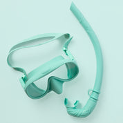The Honey Snorkel Kit by Honey Swim includes a teal snorkel and mask set on a matching background. The goggles offer a clear, panoramic view with an adjustable strap, and the snorkel has a curved design with a mouthpiece.