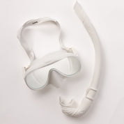 The Honey Snorkel Kit by Honey Swim includes a white mask with clear lenses for a panoramic view, and a matching snorkel with a transparent mouthpiece and streamlined design, all showcased on a light background.