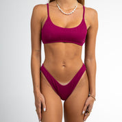 A woman models the Honey Swim Berry Ribbed Bralette Set with thin straps against a white background, wearing minimal jewelry. Her face is not visible in the image.