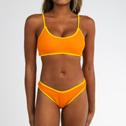 A woman models the Honey Swim Marigold Terry Bralette Set, featuring adjustable straps and yellow trim in a sporty, textured terry cloth style. She stands before a plain white background, face partially out of view.