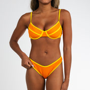 A woman models the Honey Swim Marigold Terry Classic Underwire Set with yellow trim and adjustable straps, posing against a white background with one hand on her hip and the other on her thigh.