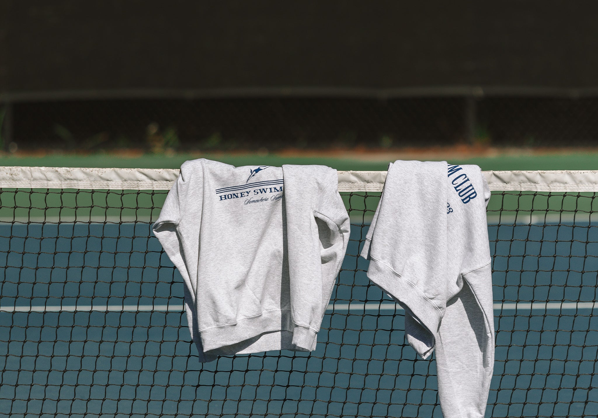 honey swim crewnecks leaning over a tennis court along the beaches on 30A Florida