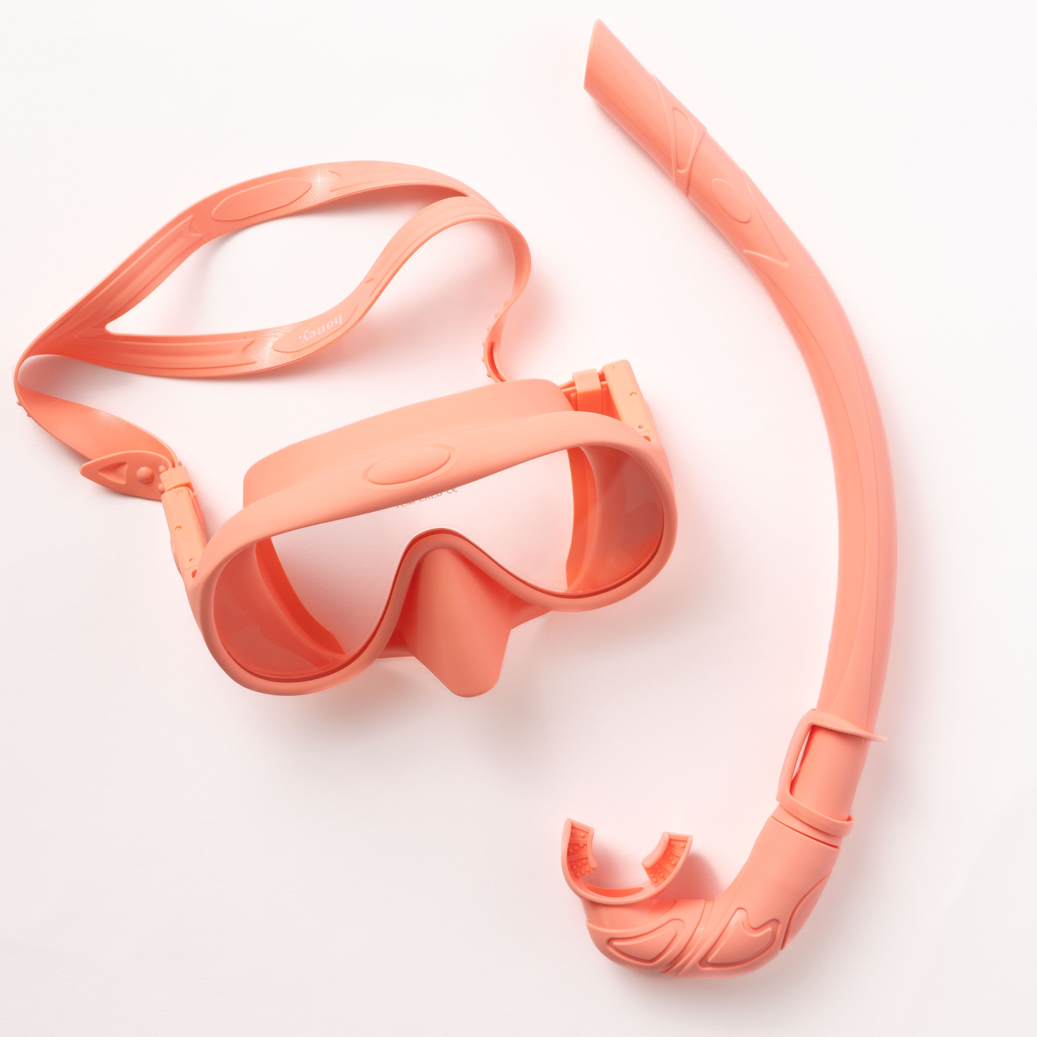 The Pink Snorkel Set by Honey Swim is showcased on a white backdrop. It offers a 180-degree panoramic mask with a broad strap and a smoothly curved snorkel designed for a leak-proof fit.