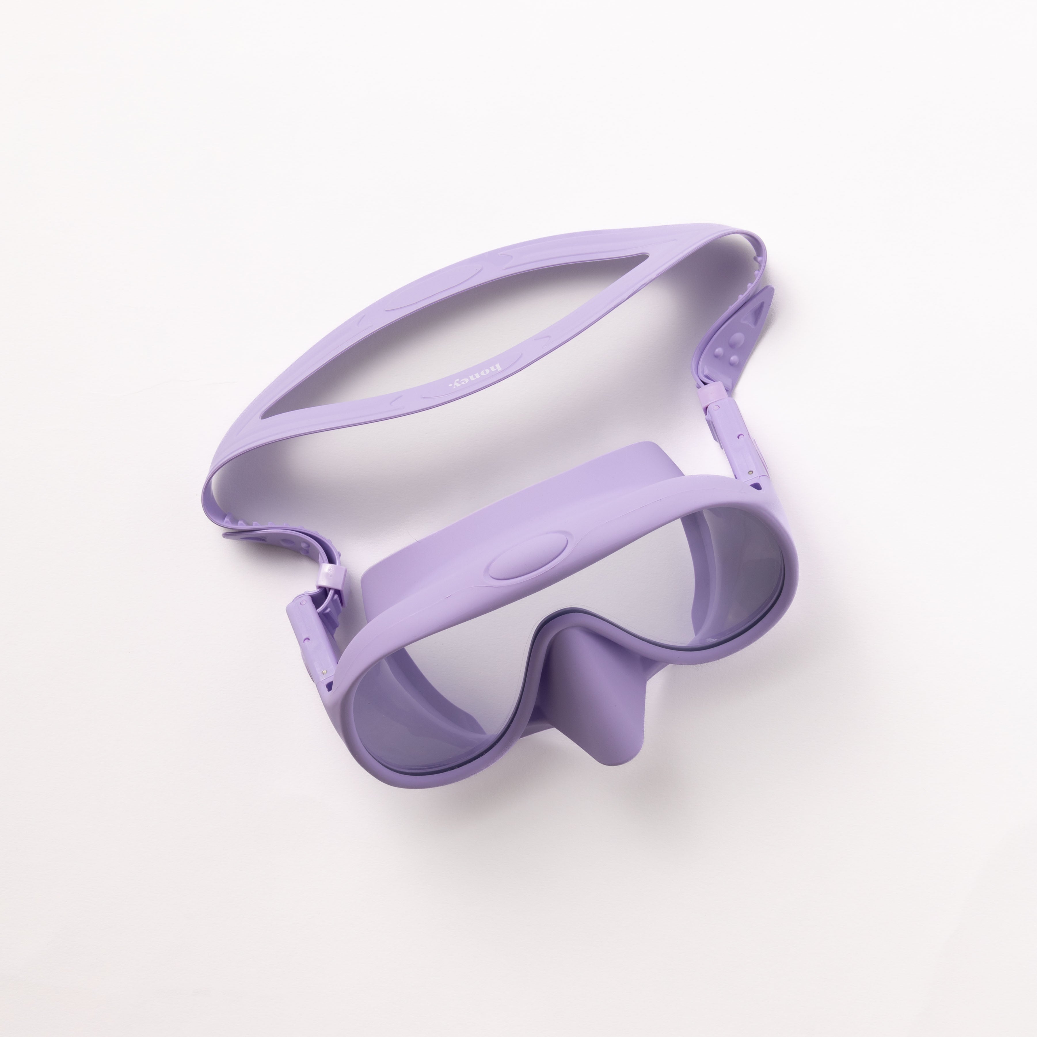 The Honey Goggles by Honey Swim, a purple snorkeling mask with a clear lens and adjustable strap, designed for a panoramic view snorkel experience, is displayed against a white background.