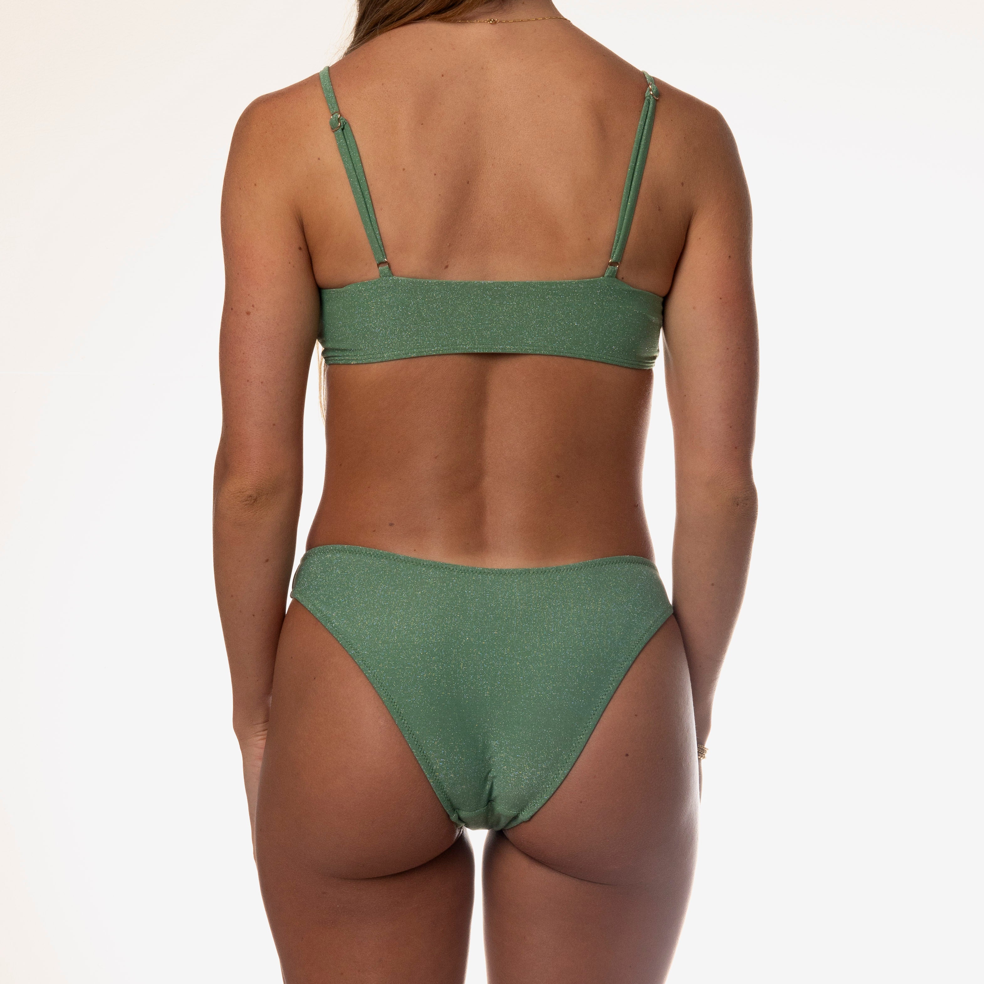 A person with long hair wears the Olive Shimmer Bralette by Honey Swim against a plain white background.