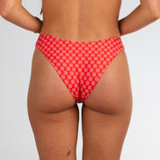A person is shown from the waist down, facing away, wearing Honey Swim’s Azalea | Classic Bottoms in red floral print—ideal for beach days—set against a plain white background.
