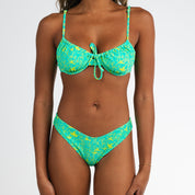 A woman models the Honey Swim Lush String Underwire Set bikini in a green, yellow, and blue retro print against a plain white background; her face is not shown.