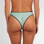 Model shown from the waist down wearing Piper Ribbed | Cheeky Bottoms by Honey Swim in green and white stripes with green trim, perfect for summer tanning, against a plain white background.