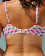 A close-up of a womans back wearing the Honey Swim Sorbet Ribbed Laced Bralette Set, featuring colorful stripes, adjustable straps, and a clasp closure. The background is out of focus.